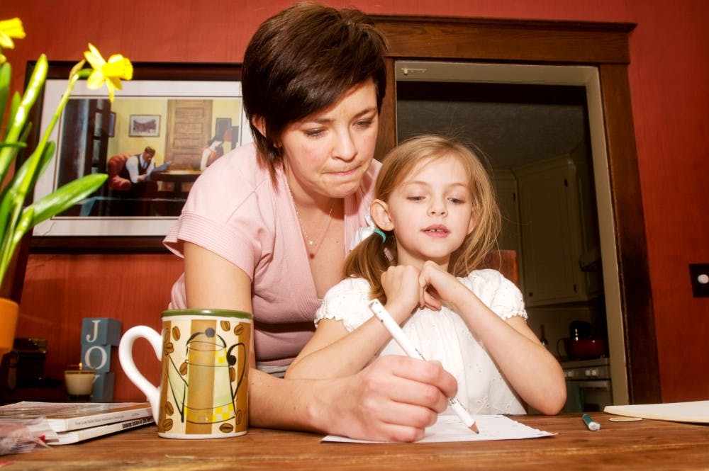 Health risk graduate student Susanna Joy helps her daughter Annabella, 7, with her math test Thursday afternoon at their Lansing home. Joy is a graduate student who also home-schools her three children.