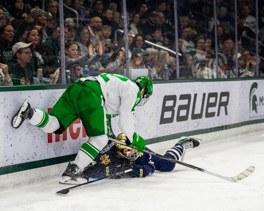 MSU Fr. F, Porter Martone (22), puts a Notre Dame player on the ice after getting pushed into the wall in Munn Ice Arena in East Lansing, MI on Feb. 19, 2026.