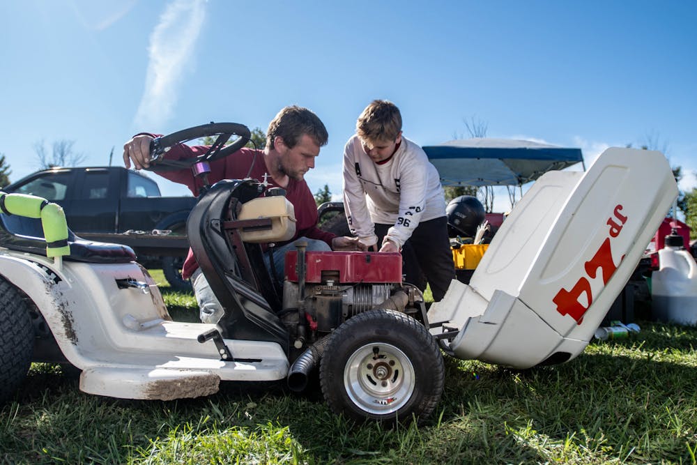 <p>Chase Morrison, left, and his son Cayden Morrison, right, tune one of their three racing mowers in Potterville, Michigan, on Sept. 19, 2020.</p>