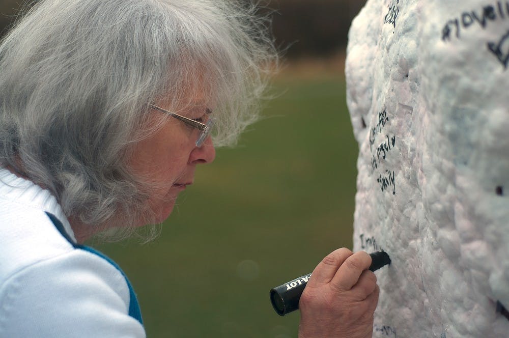 <p>Eaton Rapids resident Carolyn Sayer signs the rock on Farm Lane in memory of her granddaughter Lacey Holsworth April 8, 2015. "She was a very special little girl," Sayer said. "We miss her terribly but she's in heaven with Jesus now." Kelsey Feldpausch/The State News</p>