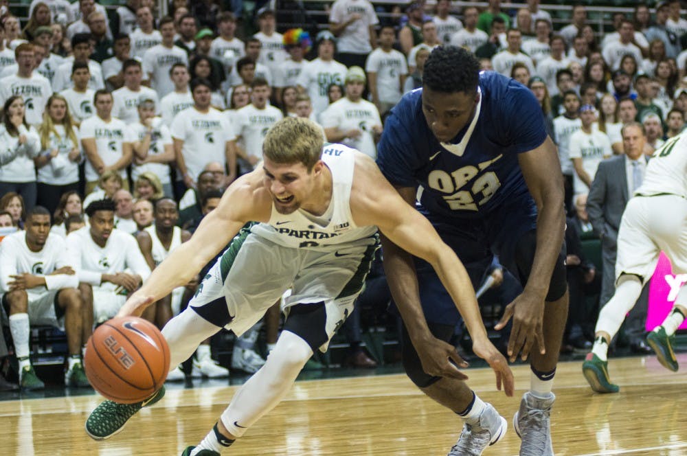 Sophomore guard and forward Kyle Ahrens (0) and Oral Roberts forward Emmanuel Nzekwesi (23) fight for a loose ball during the first half of the men's basketball game against Oral Roberts on Dec. 3, 2016 at Breslin Center. 