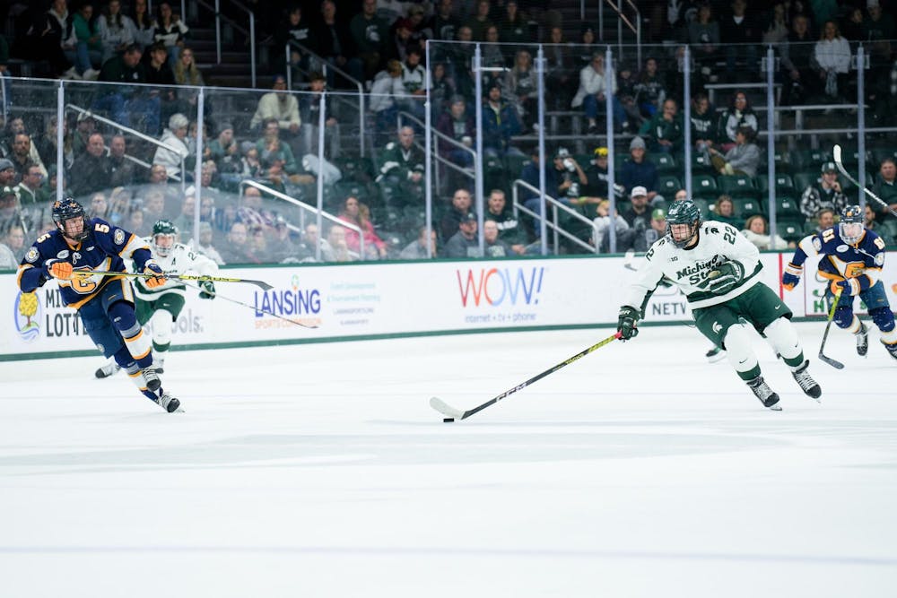 Sophomore forward Isaac Howard (22) dribbles the puck during a game against Canisius at Munn Ice Arena on Oct. 19, 2023. The Spartans beat the Griffins 6-3 in one of a two-game series.