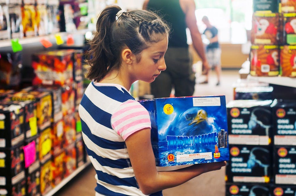 <p>Owosso, Mich., resident, Sienna Baker, 11, browses a selection of fireworks on July 2, 2014, at Jeff's Fireworks, 3340 E Lake Lansing Road. Baker plans on going to Higgins Lake, Mich., with her family to celebrate the Fourth of July. Jessalyn Tamez/The State News</p>