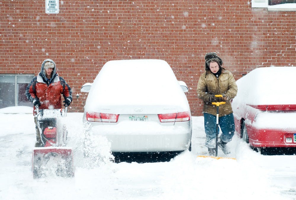 Boyd Landscape employees Don Cornell, left, and Travis Iler, right, clear snow out of an alley off of Division Ave. on Wednesday morning. The National Weather Service reported 11 inches fell on East Lansing overnight. Josh Radtke/The State News