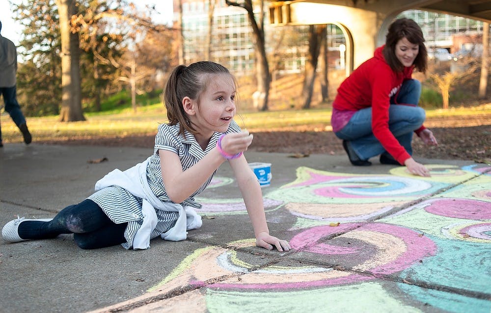 	<p>Okemos resident Ava Gavrilides, 7, draws with chalk on the sidewalk by Red Cedar River next to Main Library with Lansing resident and Lansing Community College student Shannon Smith. Smith said she draws on the pavements on <span class="caps">MSU</span> campus a few times every year for fun. Justin Wan/The State News</p>