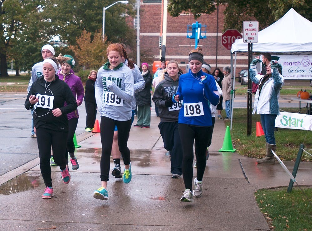 <p>Advertising senior Katie Bean, prenursing sophomore Jamie Guild and animal science senior Briana Blomstrom lead the start of the March of Dimes 5K on Oct. 26, 2013, by the Auditorium. The 5K was a fundraiser to support the adopt-a-family program of Sparrow Hopital's Neonatal Intensive Care Unit, or NICU. Georgina De Moya/The State News</p>