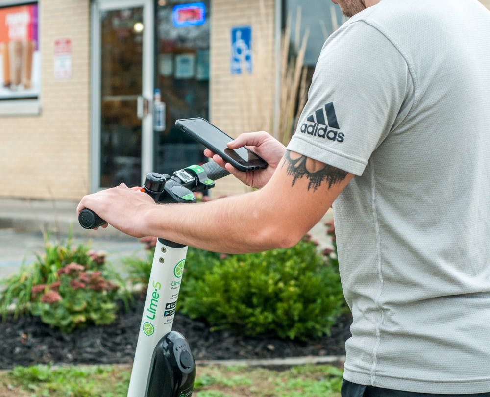 <p>Advertising management senior Dom Rea unlocks a Lime scooter using his phone Oct. 10, 2018, at Grand River Avenue.</p>