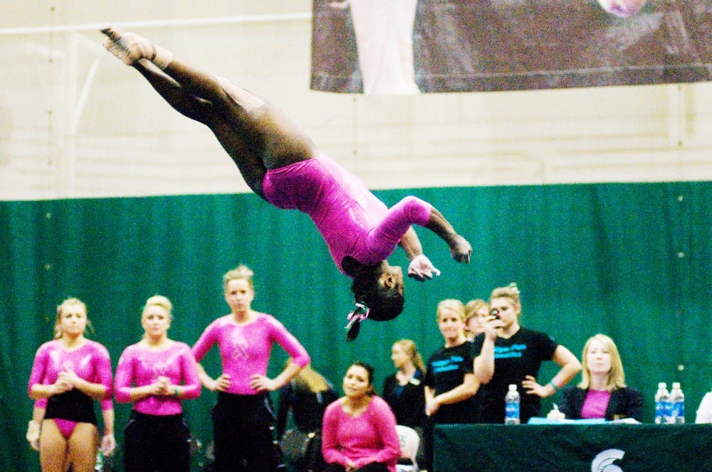 Teammates watch as sophomore Shanthi Teike performs her floor exercise on Jan. 22 against  Minnesota at Jenison Field House. Teike placed second in the all-around results with a score of 37.575. Lauren Wood/The State News
