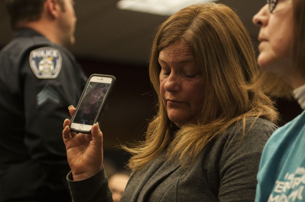 <p>Protestor Leslie Miller holds a picture of her daughter, Emma Ann Miller, who was assaulted by Nassar, on her phone during the Board of Trustees meeting on April 13, 2018 at Hannah Administration Building. (C.J. Weiss | The State News)</p>