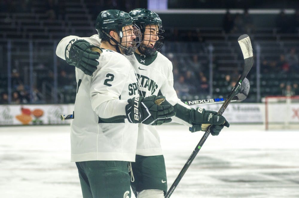 Sophomore defenseman Zach Osburn (2) and freshman defenseman Anthony Scarsella (4) celebrate after Osburn's goal during the third period in the exhibition game against U.S. National Team Development Program U-18 Program on Dec. 4, 2016 at Munn Ice Arena. The Spartans defeated the U.S. National Team Development Program U-18, 5-1.