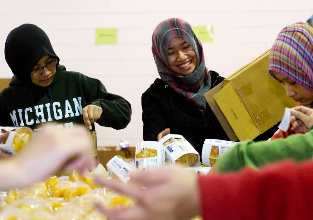 Biochemistry sophomore Fatin Shukri, right, smiles as she works alongside biochemistry/biotechnology senior Mimi Ismail Monday at the Mid-Michigan Food Bank, 2116 Mint Road, Lansing.   The students, members of the Malaysian Students Organization, volunteered at the food bank for Martin Luther King Jr. Day.  Katy Joe DeSantis/The State News