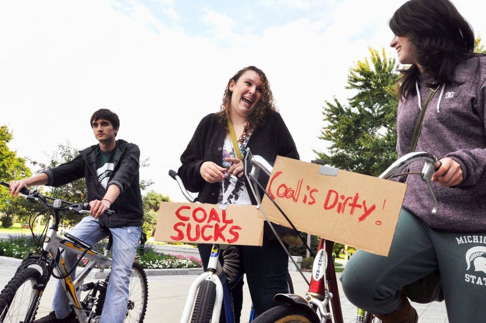 From right; history, philosophy and sociology of science sophomore Jordan Lindsay, Residential College in the Arts and Humanities freshman Leah Singman and chemistry freshman Kevin Adams prepares for the Moving Planet protest in front of Administration Building Saturday evening. Justin Wan/The State News