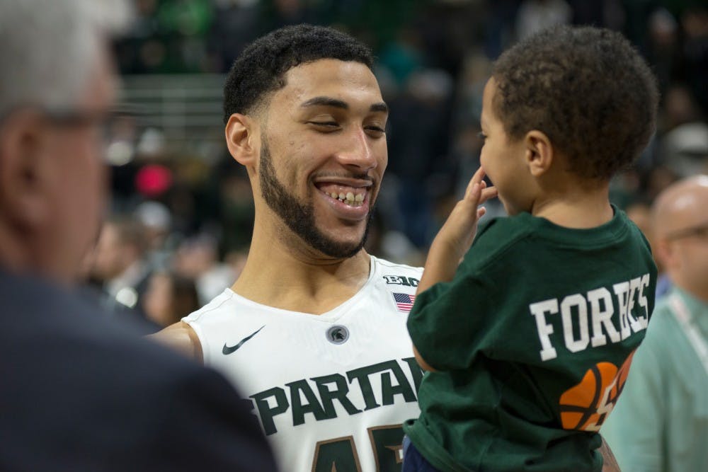 Senior guard Denzel Valentine holds senior guard Bryn Forbes' son, Carter, after the game against Ohio State on March 5, 2016 at Breslin Center. The Spartans defeated the Buckeyes, 91-76.