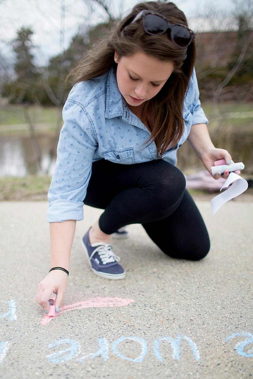 	<p>French senior Daphney Weatherup writes a poem titled &#8220;Rough Honey&#8221; with chalk April 15, 2013, along the Red Cedar River behind Shaw Hall. The event was hosted by the <span class="caps">RCAH</span> Center for Poetry and the <span class="caps">MSU</span> Sexual Assult Program. Natalie Kolb/The State News</p>