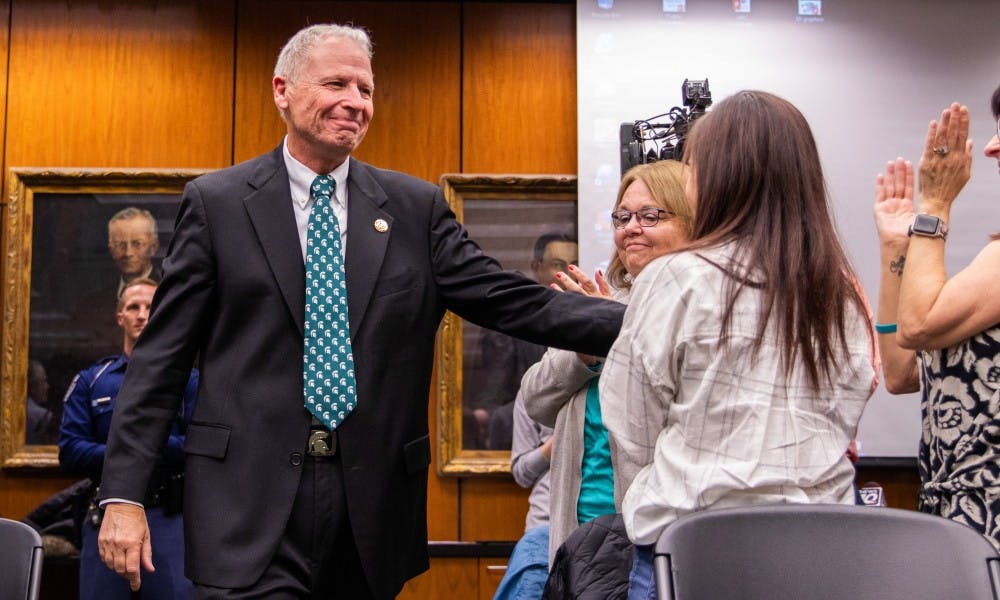 <p>Former MSU Police Chief Jim Dunlap walks to the front of the Board of Trustees meeting Dec. 14, 2018 at the Hannah Administration Building.</p>
