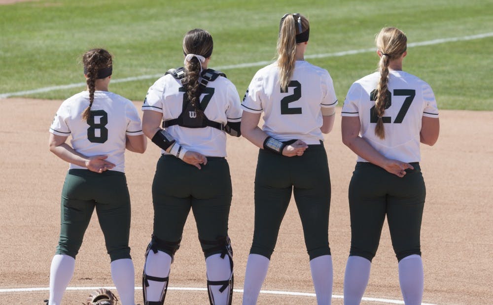 From left, junior third baseman Kaitlyn Eveland (8), designated player Kelcey Carrasco (17), Senior redshirt pitcher Kristina Zalewski (2), and Freshman first baseman Riley Paxson (27) stand for the national anthem before the game against Central Michigan on April 25, 2018. The Spartans defeated the Chippewas, 8-1.
