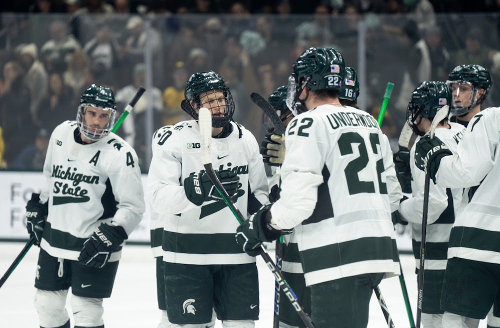 Freshman forward Daniel Russell (20) and graduate student defender Michael Underwood (22) high-five each other after a victory over the University of Michigan at Munn Ice Arena on Dec. 9, 2022. The Spartans defeated the Wolverines 2-1. 