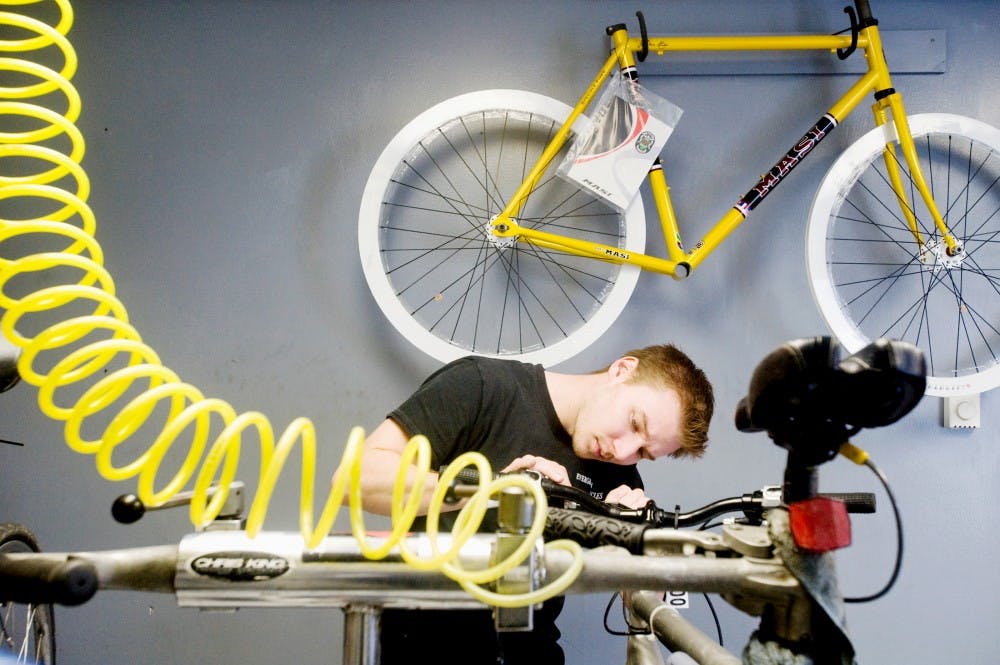 Evergreen Cycles and Repair owner Hunter Seyfarth replaces a bike break Wednesday afternoon at his shop at 314 Evergreen Ave. His business has been around since October 2006 and has seen bike shops around the area come and go. Justin Wan/The State News