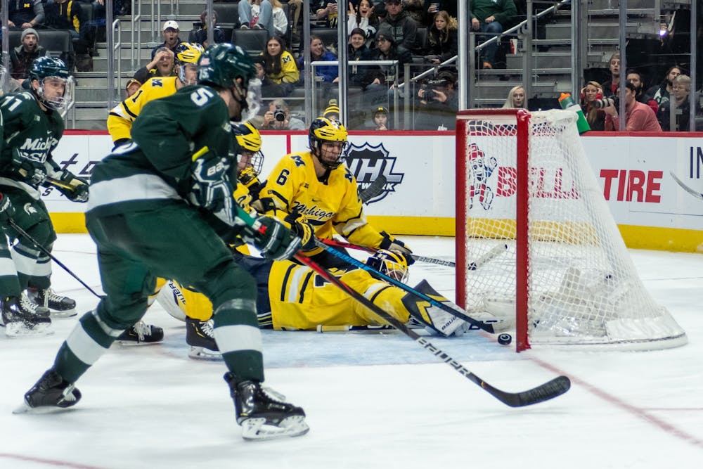 <p>Then-Michigan goalkeeper Strauss Man (bottom) and right wing Nolan Moyle (behind #5) dive to keep a Michigan State shot out of the net. The Spartans fell to the Wolverines, 1-4, at Little Caesars Arena on Feb. 17, 2020. </p>