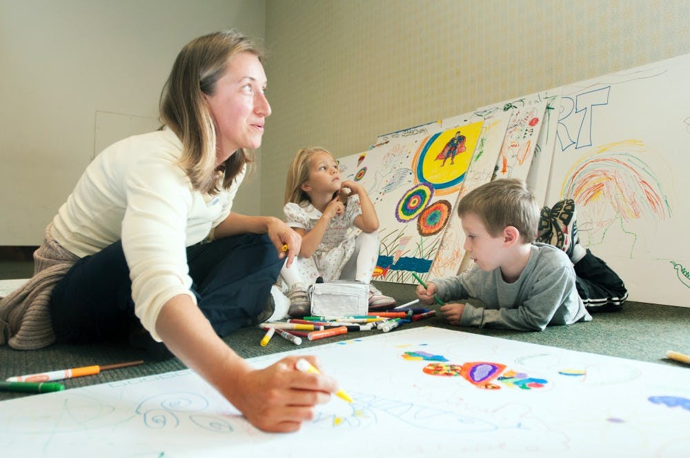 East Lansing residents Daniela, left, 5-year-old Nina and 6-year-old Matthew Vanotteren color on a large piece of paper that will help build the Broad Art Museum float on Saturday afternoon, Sept. 8, 2012 at the former Barnes & Noble in downtown East Lansing. The Eli and Edythe Broad Art Museum Family Day focused on creative projects. Natalie Kolb/The State News