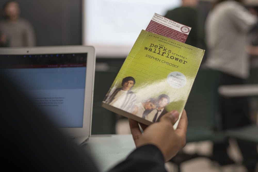A student holds up "The Perks of Being a Wallflower" during Sigma Tau Delta's Banned Book Night at Wells Hall on April 21, 2025.