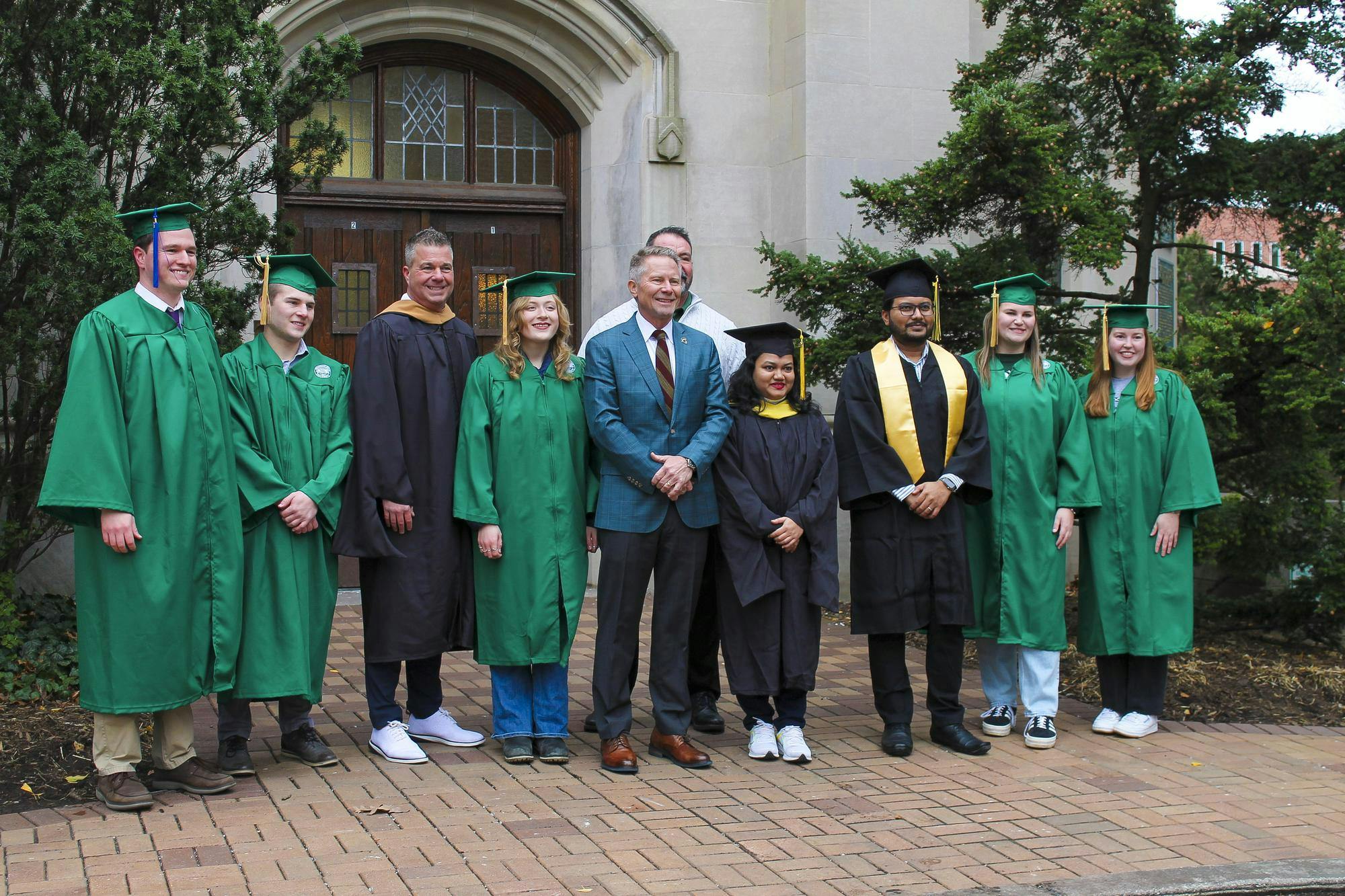 MSU President Kevin Guskiewicz poses for a picture with graduating Spartans at Beaumont Tower, a part of the "Beaumont Tower Climb" on Dec. 11, 2024.