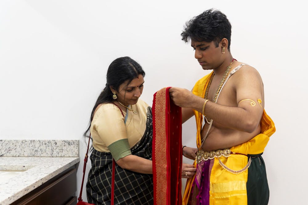 Abhinav Anand’s auntie Anu Iyengar helps him organize his costume before his performance in a dressing room in the Sri Sharadamba Temple in Farmington Hills, Mich. “It is nice to see him do some experiments and bring some new things,” she said. 