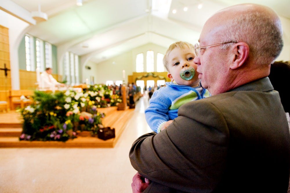 Dennis Fisher, of Dayton, Ohio., holds his 15-month-old grandson, Benjamin, of Holt, Mich. on Sunday morning at St. John Church and Student Center, 327 M.A.C Ave. Sunday was Easter Sunday, a religious celebration for Christians and Catholics. Justin Wan/The State News