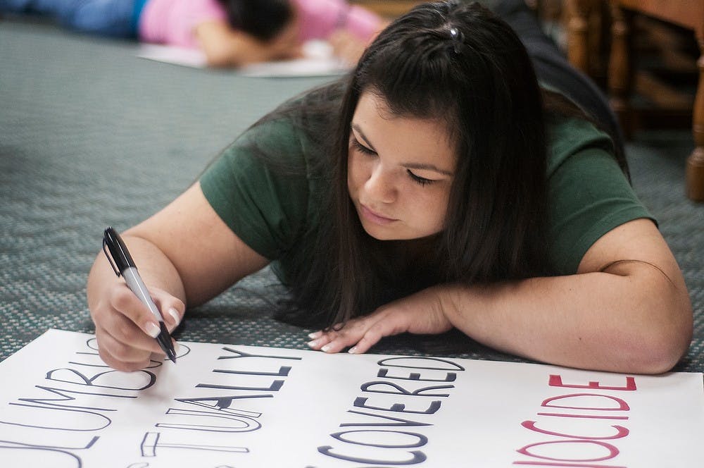 	<p>Lansing resident Bleu Bird draws a Columbus Day protest sign during a North American Indigenous Student Organization meeting Sunday, Oct. 7, in Hubbard Hall. <span class="caps">NAISO</span> is raising awareness for Indigenous People&#8217;s day across campus on Monday. Adam Toolin/The State News</p>