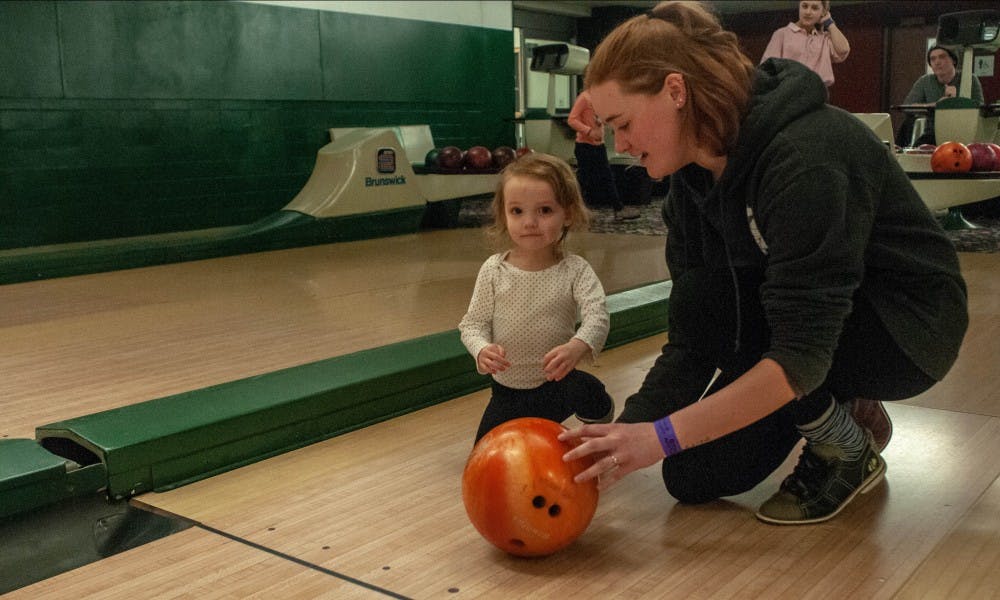 <p>Computer science junior Emma Taylor, right, helps Ruby Taylor, 2, left, bowl at the Sibs and Kids event at the MSU Union on Feb. 8, 2019.</p>