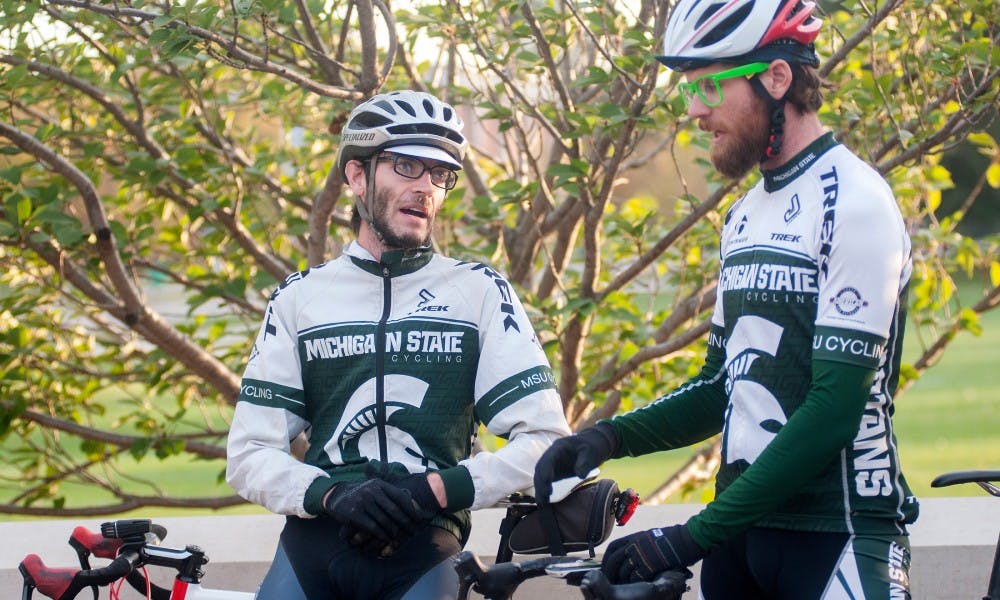 <p>Horticulture graduate students Stefan Cerbin, left, and Brian Poel get ready to go on a ride with the MSU Cycling Club on Oct. 19, 2015 at the Sparty Statue. The group usually has around eight participants that ride around campus and surrounding towns.</p>