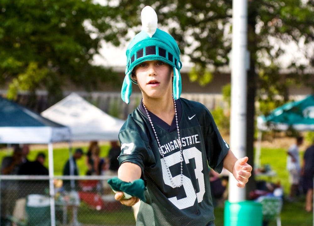 	<p>Kyle Switzer, 9, plays against his father in a bean bag toss while tailgating before the football game against Youngstown State on Friday. Mo Hnatiuk/The State News</p>