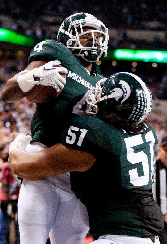 Junior offensive tackle Fou Fonti celebrates with junior running back Edwin Baker after he scored a toucdown. The Spartans lost to the Wisconsin Badgers, 42-39, in the Big Ten Championship game on Saturday night at Lucas Oil Stadium in Indianapolis, Ind. Josh Radtke/The State News