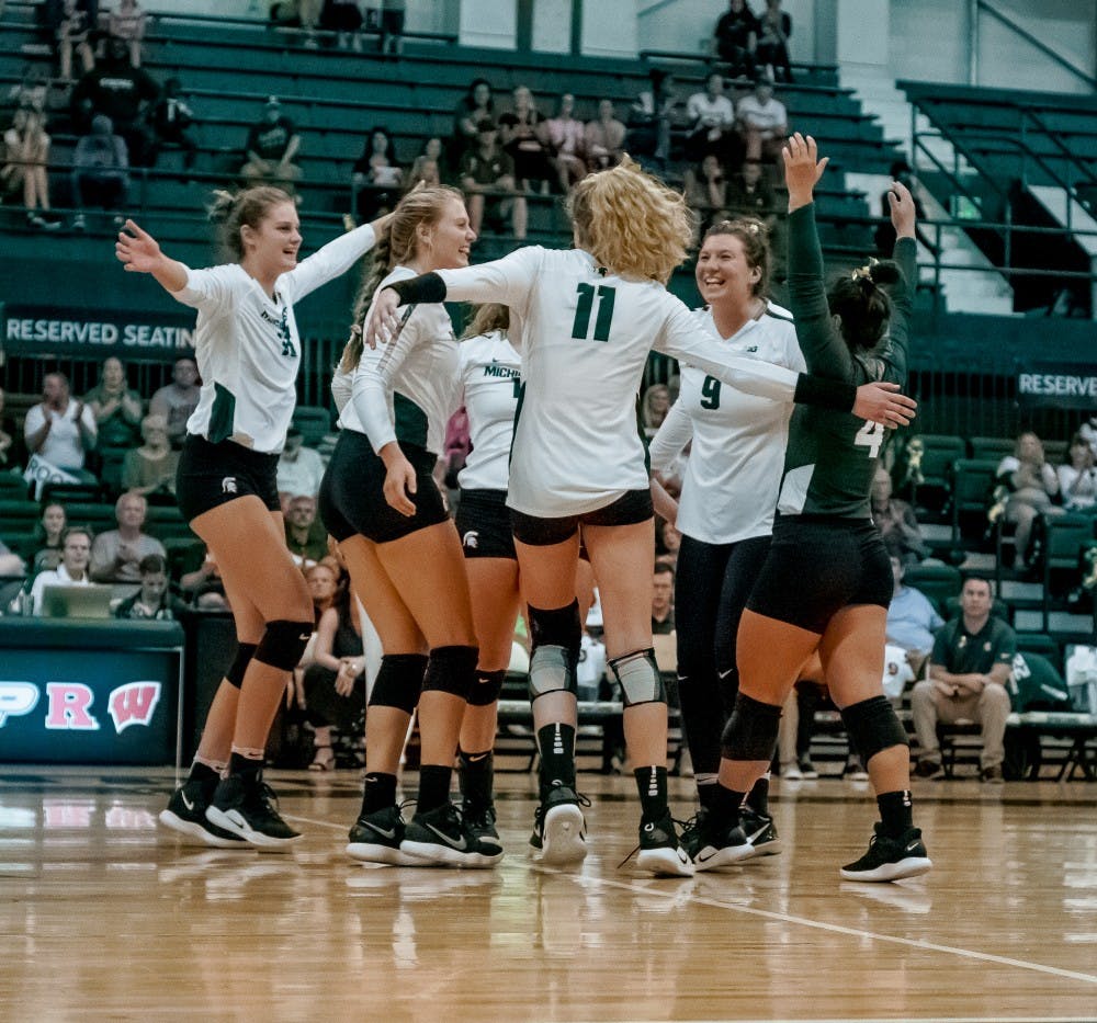 The Spartans celebrate with each other after a point during the game against Albany on Sept. 14, 2018 at Jenison Fieldhouse. The Spartans defeated the Great Danes, 3-0.
