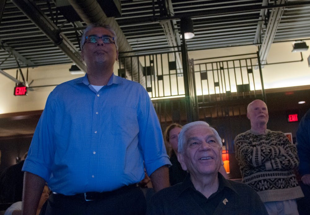 Democratic candidate for Michigan State Representative Sam Singh, left, views voting results during an election watch party on Nov. 8, 2016 in Pizza House at 4790 S. Hagadorn Rd.