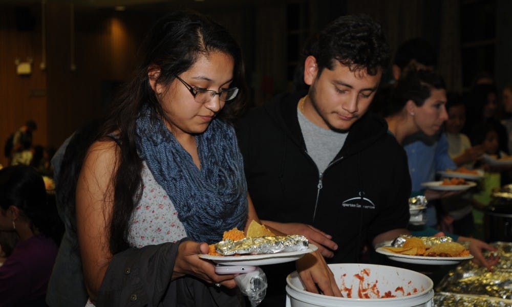 <p>Elementary education junior Cynthia Martinez and construction management junior Roberto Villela serve themselves during MICCA's Day of the Dead celebratory event on Nov. 2, 2015 at the Erickson Kiva.</p>