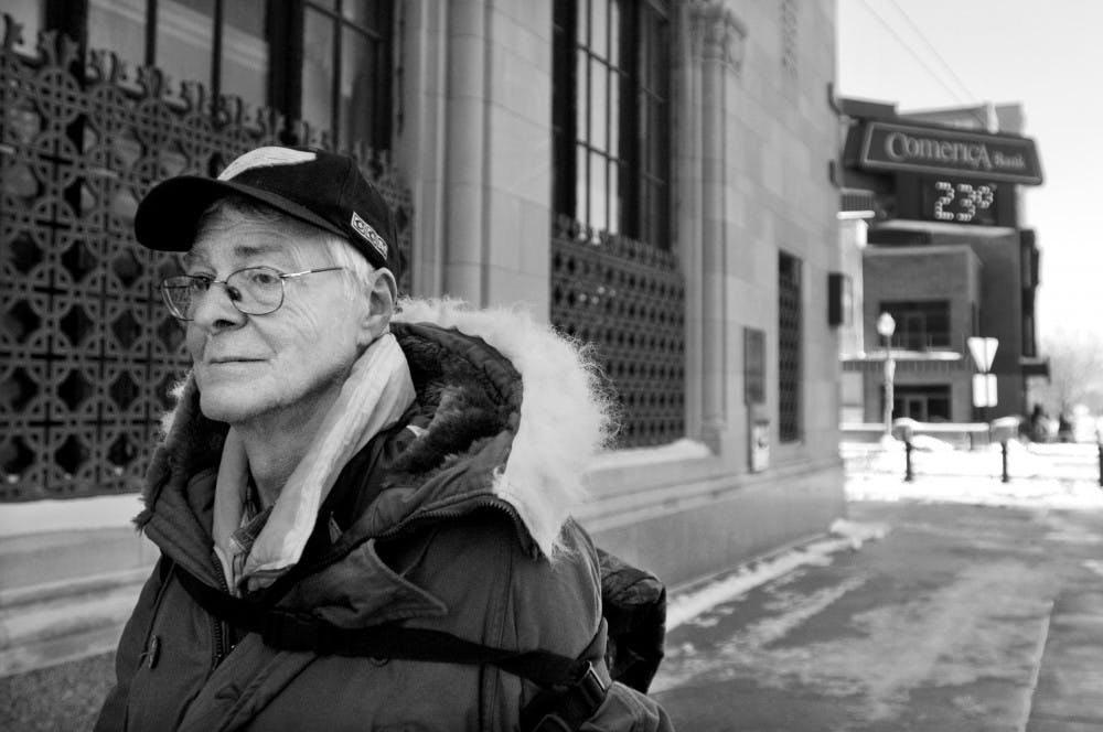 Lansing resident Richard Aikin walks past downtown businesses as the temperature reads 23 degrees Fahrenheit on Friday in Lansing. To stay warm Aikin usually goes to a nearby church or coffee shop. "I take my life one day at a time," he said. "I just take off walking. If the church is open I'll make a quick stop there to get warm." Kat Petersen/The State News