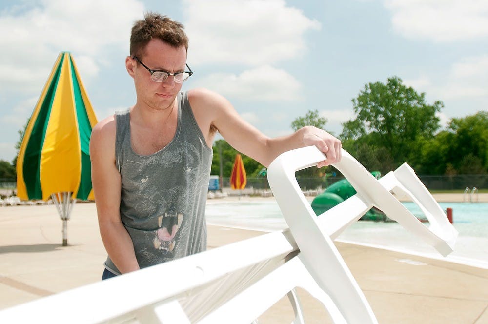 	<p>Media and information senior Nick Mackley sets up a chair May 29, 2013, in preparation for the opening of the East Lansing Family Aquatic Center, 6400 Abbot Road. The center will open May 31, 2013, for the summer season. Weston Brooks/The State News</p>