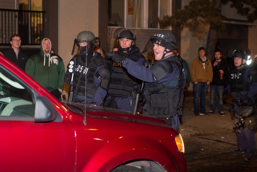 East Lansing police officers signal to a car that it must back up on Dec. 5, 2015 in Cedar Village. Hundreds of students gathered in the streets of Cedar Village to celebrate MSU's victory over Iowa in the Big Ten championship. 