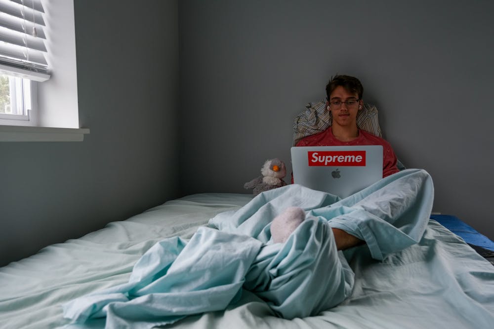 <p>Logan McCutcheon in bed during a Zoom class on Sept. 9, 2020. (Photo by: Lauren Snyder)</p>