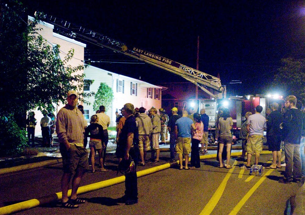 <p>Residents and neighbors linger in the street after a fire erupted at 129 Burcham Apartments late Monday night. Leo Allaire, not pictured, was one of 12 East Lansing firefighters dispatched to the fire, which spread through the walls of the apartment complex and damaged three units. All residents were evacuated and unharmed.</p>