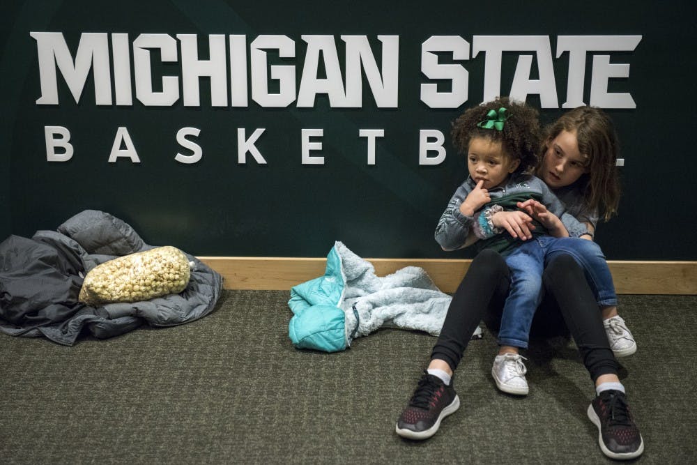 Ayanna Tillman, 2, waits with Quinn Fife, 9, of East Lansing, for her father, sophomore forward Xavier Tillman (23), to come out of the locker room after the men's basketball game against Ohio State at Breslin Center on Feb. 17, 2019. The Spartans defeated the Buckeyes, 62-44. Nic Antaya/The State News