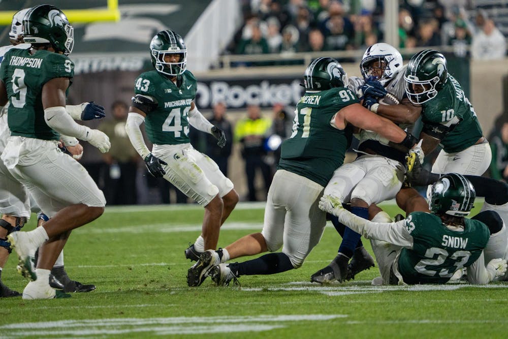 Michigan State defenders swarm to stop a Penn State ball carrier at Spartan Stadium in East Lansing, Mich., on Saturday, Nov. 16, 2025.