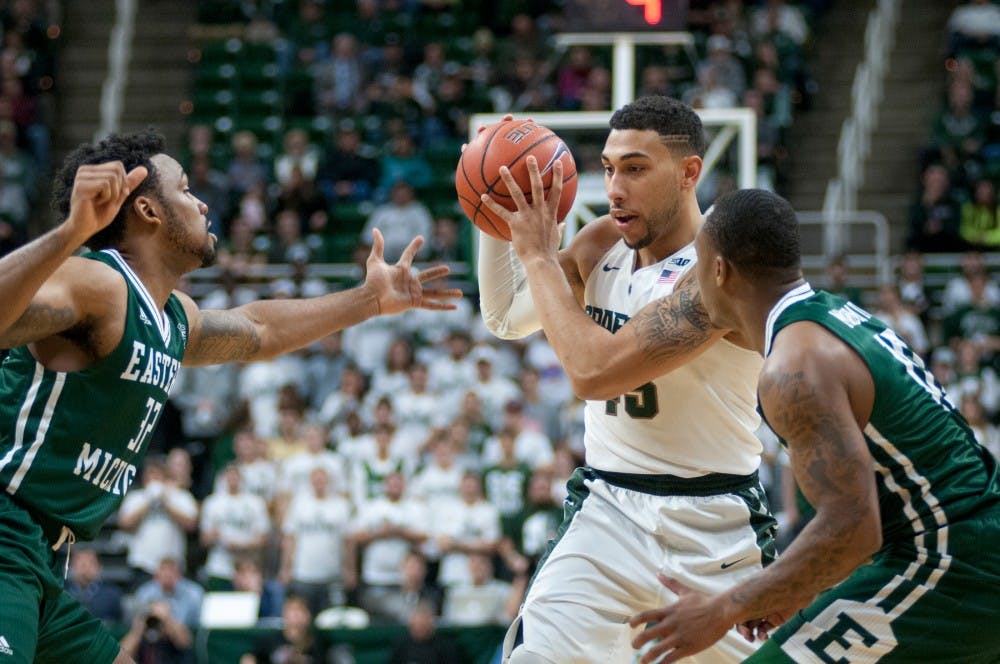 Senior guard Denzel Valentine keeps the ball away from Eastern Michigan guard Ty Toney, left, and Eastern Michigan guard Willie Magnum IV as they defend during the first half of the game against Eastern Michigan on Nov. 23, 2015 at Breslin Center. The Spartans defeated the Eagles, 89-65.