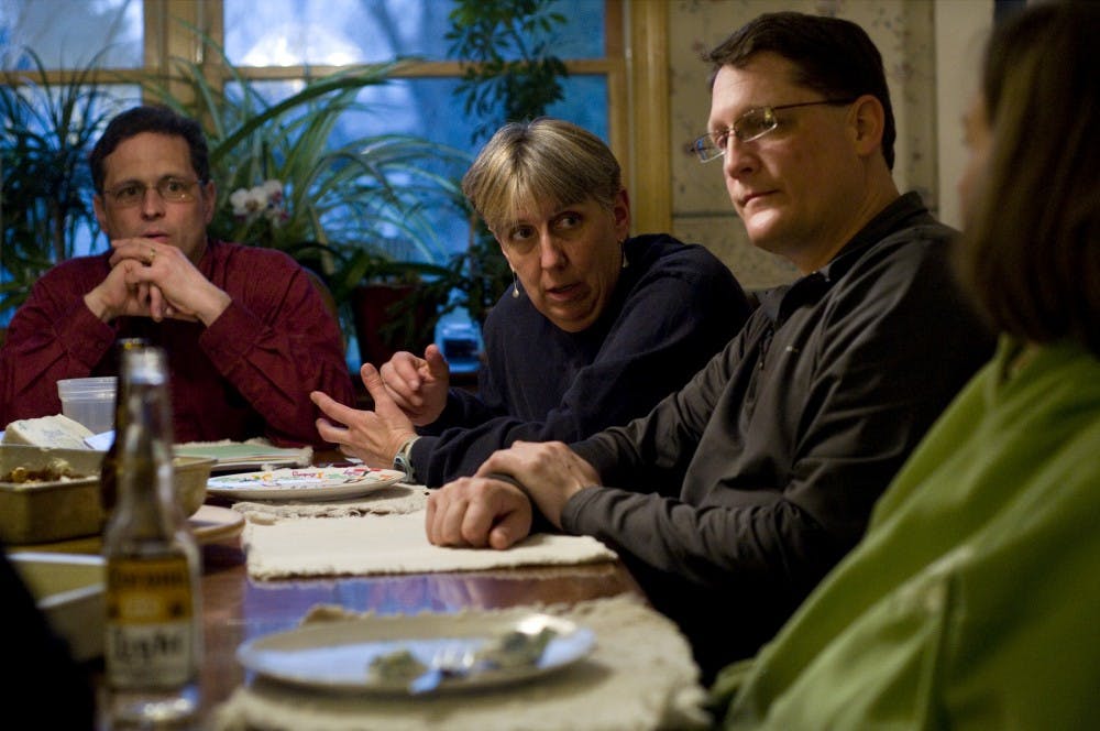 From left, Michael Waldo of Grand Ledge, Mich., Carol McEllhiney-Luster, Matt Mozurkewich, and Lisa Stahlberg of Lansing talk after dinner Sunday at McEllhiney-Luster's home in East Lansing. One of the things McEllhiney-Luster enjoys about puppy raising is the friends she makes through the program. "It's our own little dog world," she said. Matt Radick/The State News