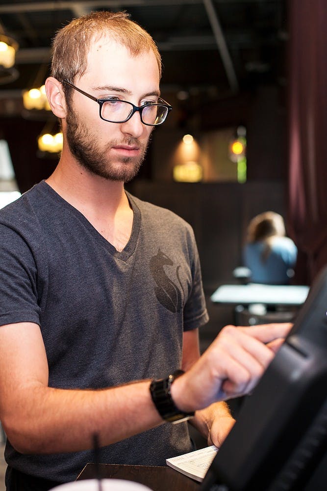 <p>Alumnus and East Lansing resident Seth Zundel serves food July, 30, 2014, at Black Cat Bistro in East Lansing. Zundel graduated with a degree in english in May, 2013 and is currently a server at Black Cat Bistro. Corey Damocles/The State News</p>