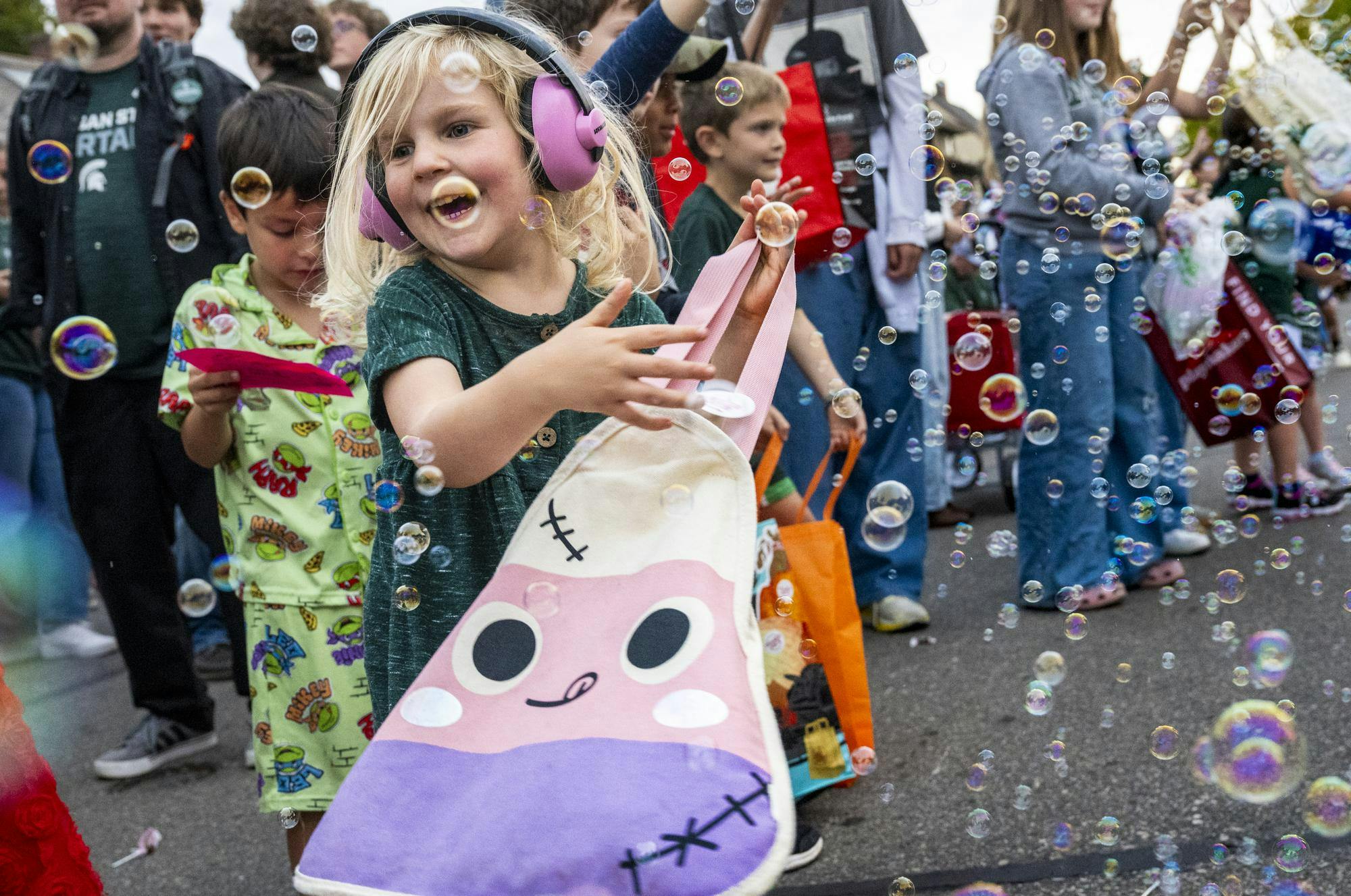 <p>Adeline Magen, 4, of East Lansing, plays with bubbles during Michigan State University’s homecoming parade along Abbot Road in East Lansing, Mich., on Friday, Oct. 9, 2026.</p>