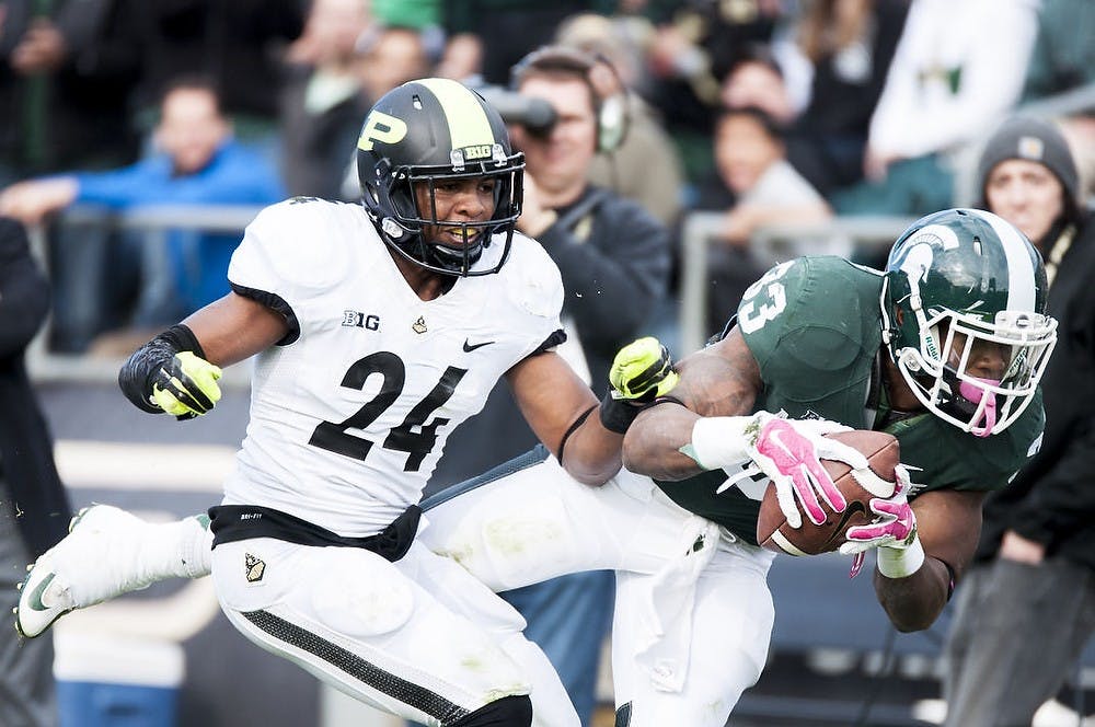 <p>Senior running back Jeremy Langford dives past junior defensive back Frankie Williams Oct. 11, 2014 during a game against Purdue at Ross-Ade Stadium. The Spartans defeated the Boilermakers, 45-31. Photo courtesy of Purdue Exponent/Mujtabaa Hasan</p>