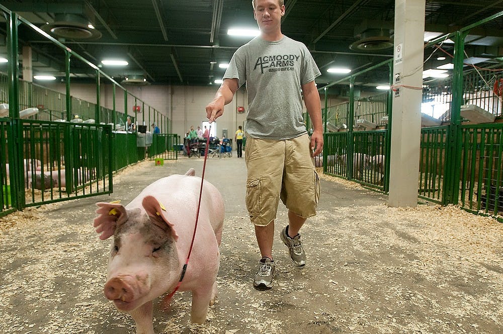 	<p>Union City, Mich., resident Adam Acmoody walks his pig to get washed off before showing July 14, 2013, at the Michigan Livestock Expo at Pavilion for Agriculture and Livestock Education. Acmoody&#8217;s pig was almost six months old and weighed 290 pounds. Weston Brooks/The State News</p>