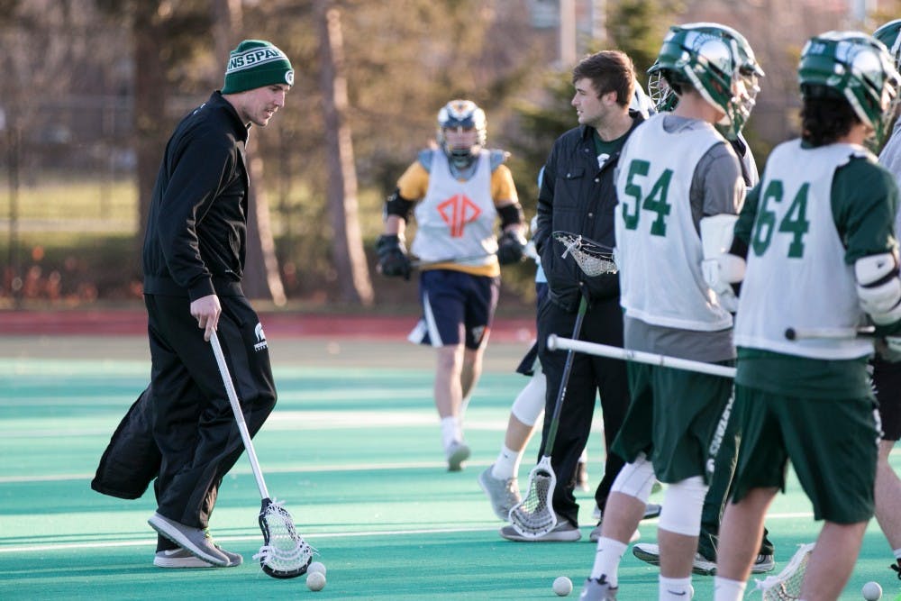 Men's lacrosse coach Cam Holding walks down the field as he prepares to run drills for players during practice on April 11, 2016 at Ralph Young Field.  Holding is professional lacrosse player in two different leagues and is the founder of Power Play Lacrosse, a youth club program based out of Lansing, Mich. that he founded in 2009.